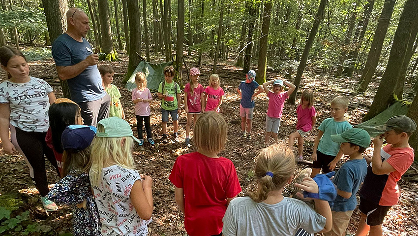Kinder bilden einen Kreis, stehen im Wald