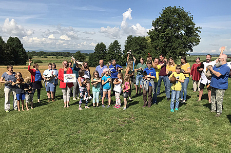 Erste Kreisbeigeordnete Stephanie Becker-Bösch hält das Label „Vielfalt Wetterau! Region für ALLE!“ in der Hand. Mitglieder des Geflügelzuchtvereins Bingenheim haben Hühner auf dem Arm.