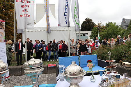 viele Menschen stehen vor den gehissten Flaggen um ein Zeichen für Toleranz, Respekt und Vielfalt zu setzen.