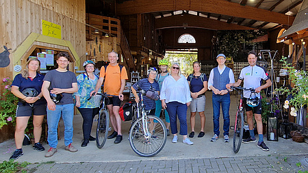 Mehrere Personen stehen nebeneinander. Drei von ihnen haben ein Fahrrad neben sich.