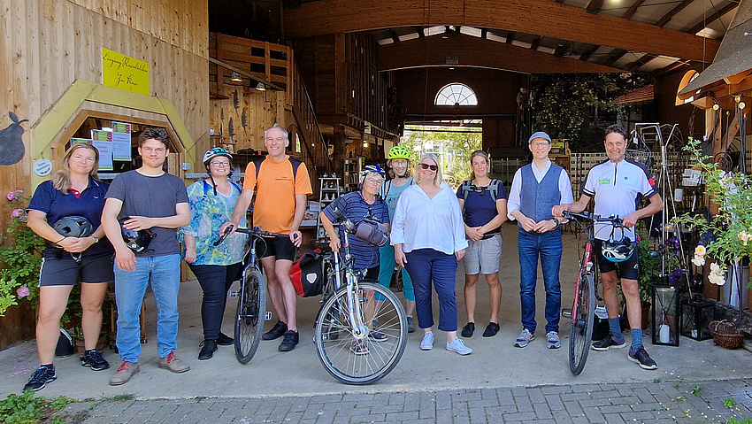 Mehrere Personen stehen nebeneinander. Drei von ihnen haben ein Fahrrad neben sich.