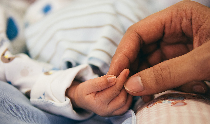 Die Hand einer Frau hält die Hand eines Babys