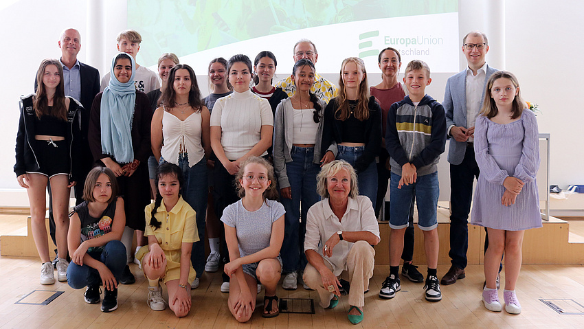 Kinder, Jugendliche und Erwachsene stehen zu einem Gruppenfoto in zwei Reihen hintereinander. Die Kinder und eine Erwachsene vorne in der Hocke.