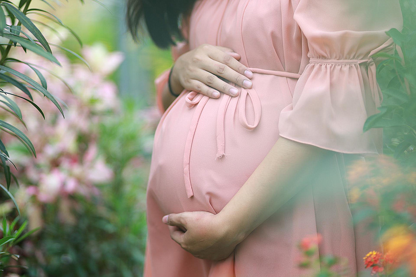 Bauch einer Schwangeren im Sommerkleid