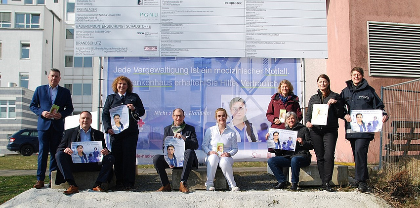 Frauen und Männer vor einem großen Banner.