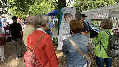 Interessierte Menschen vor dem Stand des Cochlear-Implantat-Verbandes Hessen Rhein-Main e.V. / Frankfurt am Main Mit der Selbsthilfegruppe, die sich in Friedberg trifft/ Foto A.Obleser