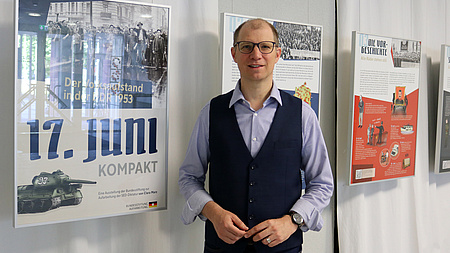 Landrat Jan Weckler vor den Bilderrahmen mit den Plakaten der Ausstellung