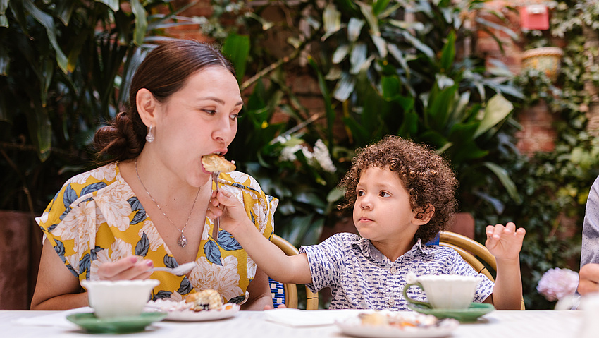 Kind füttert eine Mutter mit einem Brötchen