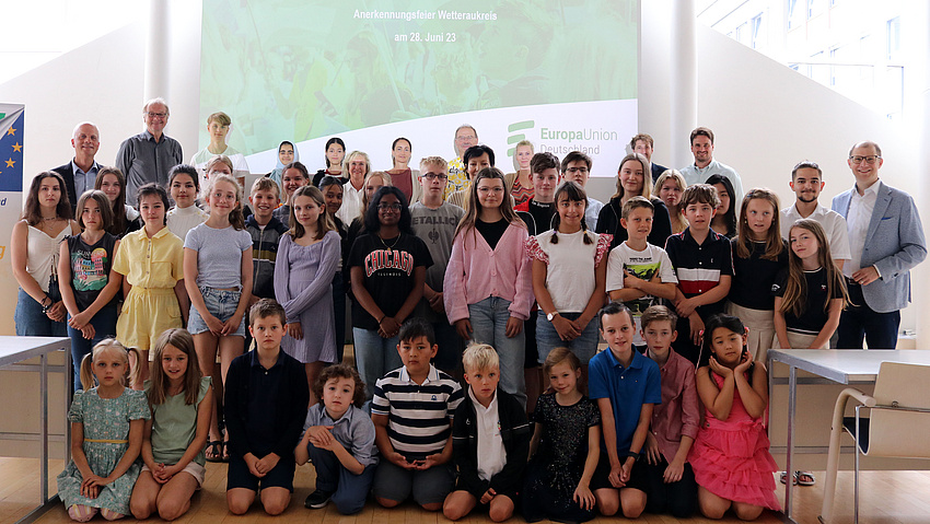 Eine große Gruppe Kinder, Jugendlicher und Erwachsener steht im Plenarsaal. Sie haben sich zu einem Gruppenfoto aufgestellt.