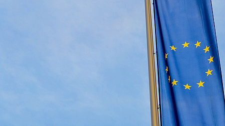 Die europäische Flagge vor blauem Himmel.