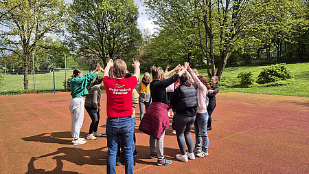 Eine Gruppe Jugendliche, die auf dem Sportplatz gemeinsam spielt