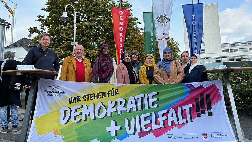 Mehrere Menschen stehen hinter einem Banner, auf dem dem steht: Wir stehen für Demokratie und Vielfalt.