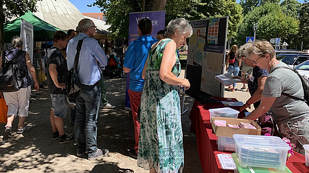 Das Fotos zeigt mehrere Personen an einem Infostand