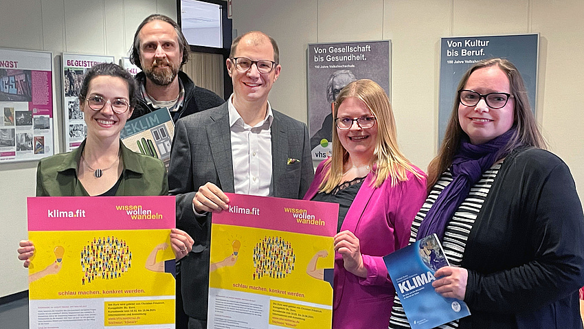 Zwei Männer und drei Männer stehen nebeneinander und halten Plakate in der Hand.