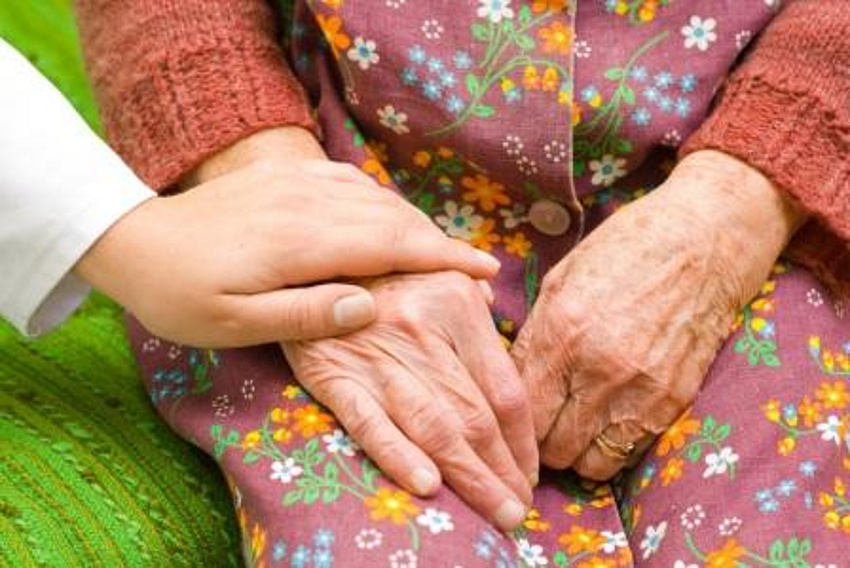 eine jüngere Hand liegt auf der Hand eines älteren Menschen