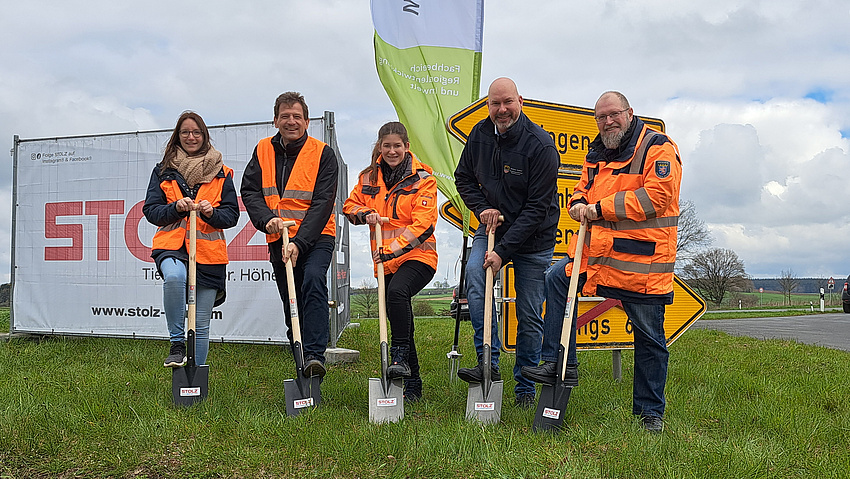 Die Personen stehen jeweils mit einem Fuß auf dem Spaten.